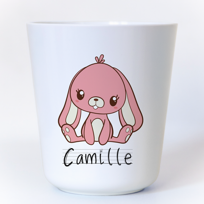 Gobelet en plastique blanc avec un petit lapin rose assis, personnalisable avec un prénom. Idéal pour les enfants, léger et incassable